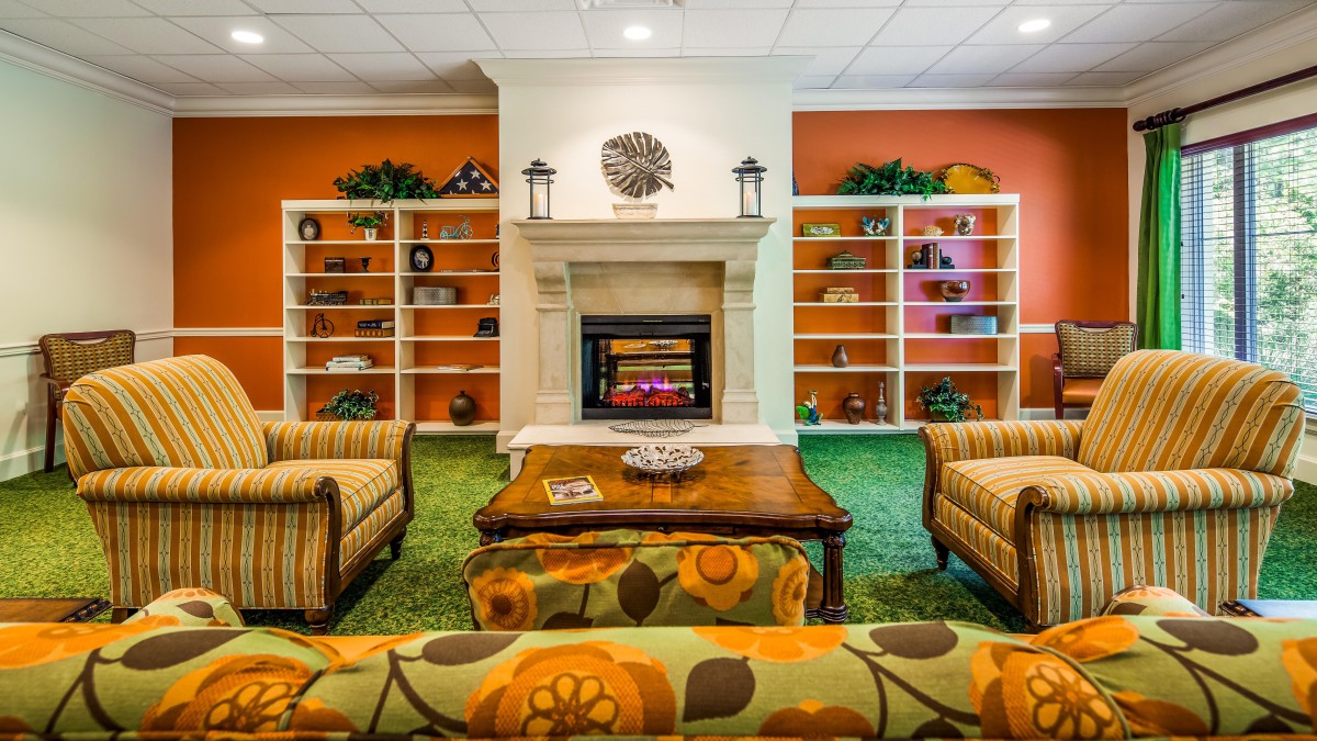 A cozy living room featuring a central fireplace, surrounded by shelves and comfortable furniture.