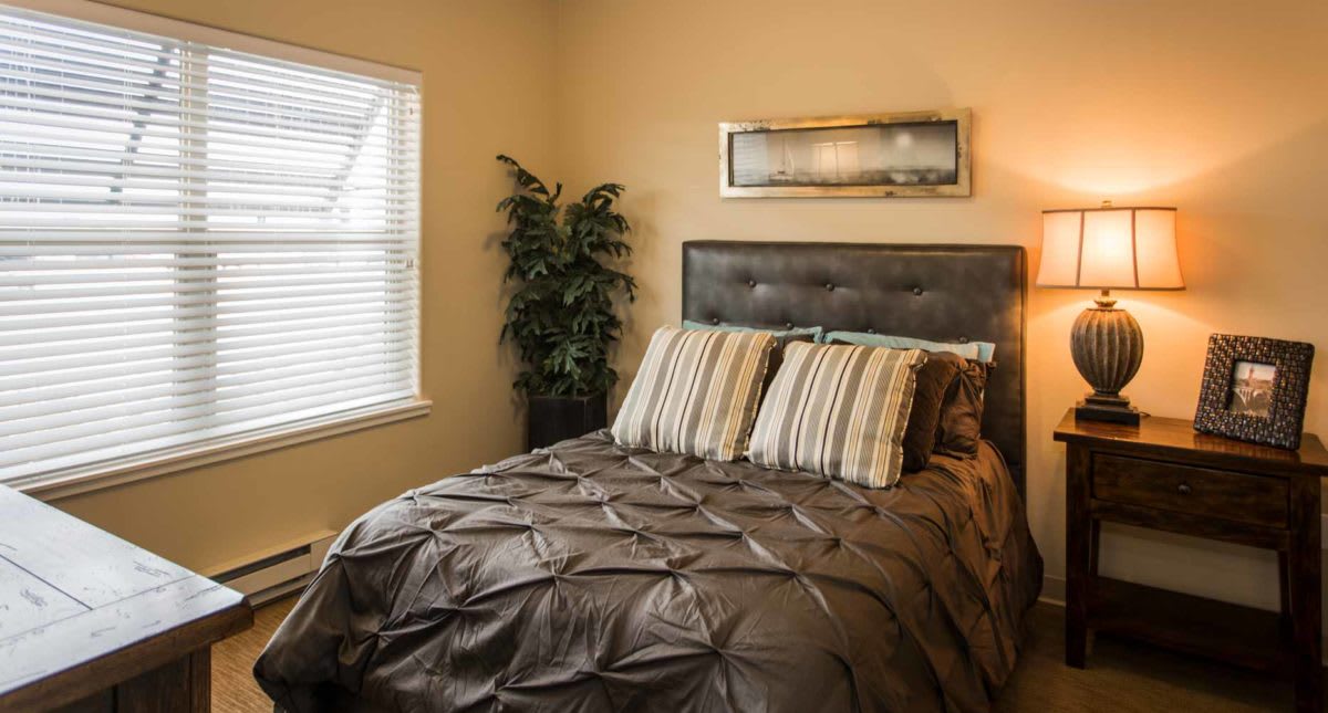 A cozy bedroom with a neatly made bed, decorative pillows, and wall art.