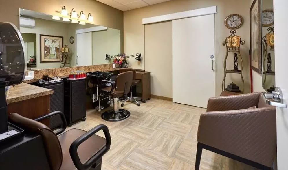 A cozy and well-arranged hair salon interior with chairs, a large mirror, and ample lighting.