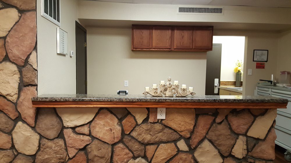 A reception desk with a stone facade and decorative candles, set in an interior space with wooden cabinets.