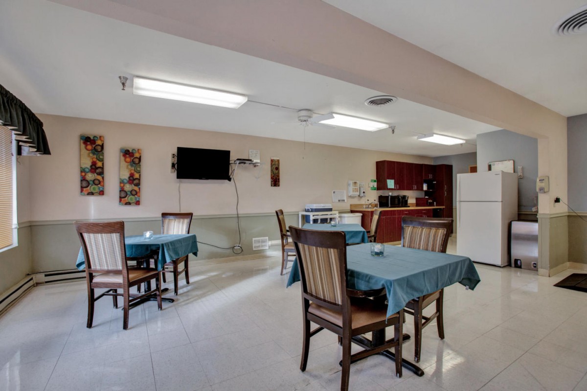 A cozy dining area with tables and chairs adjacent to a kitchen.