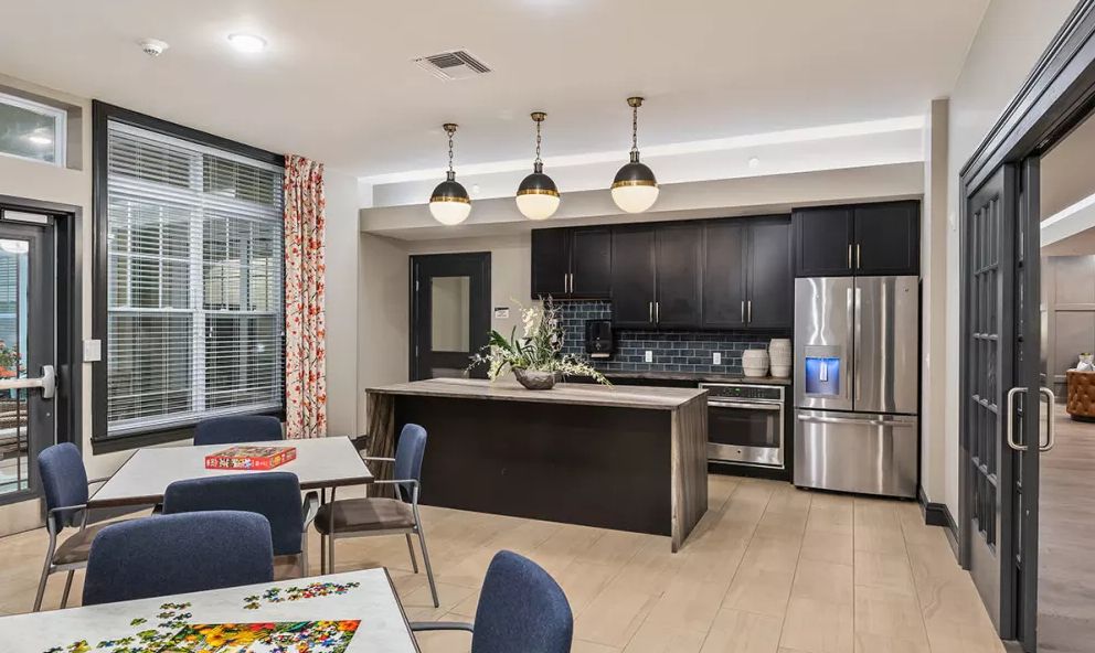 A modern kitchen with an island and pendant lighting, featuring stainless steel appliances and a dining area.