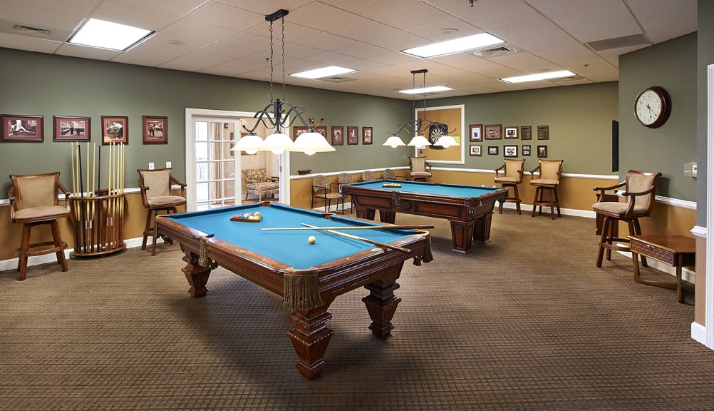 A spacious game room with two pool tables and ambient lighting.