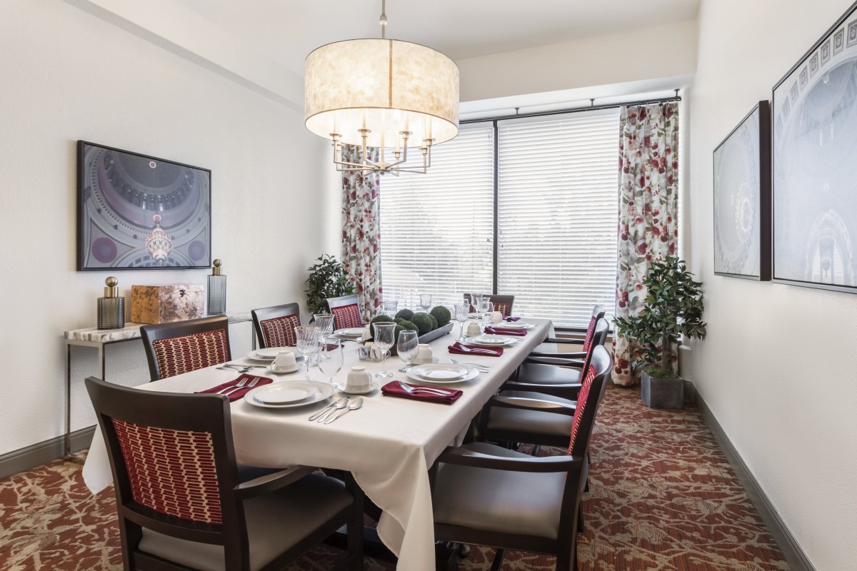 A well-appointed dining room with a large table set for a meal, featuring elegant decor and ample natural light.