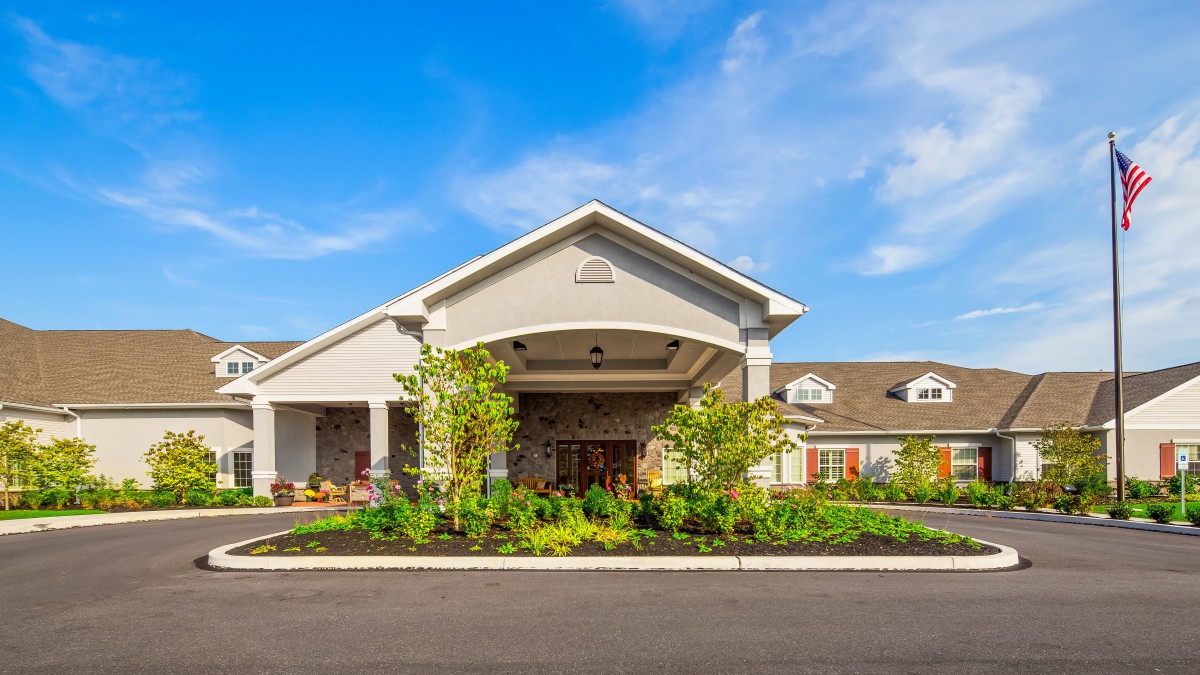 A modern building entrance with well-maintained landscaping under a clear blue sky.