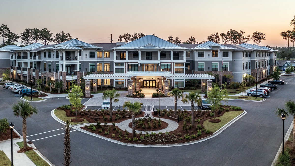 A luxurious residential building with beautiful landscaping and a grand entrance viewed during sunset.