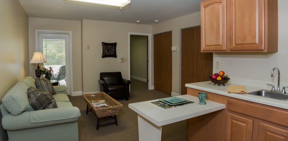 A cozy living area with a chair, coffee table, and a kitchen counter.