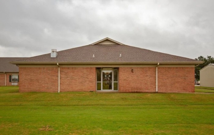 A brick building with a front lawn under a cloudy sky.