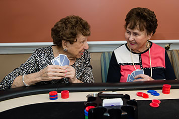 Two elderly women enjoying a card game and chatting at a table.