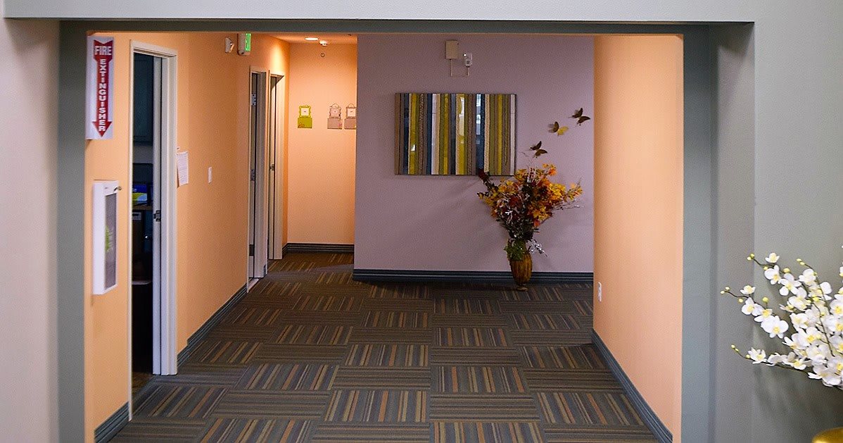 A quiet hallway with soft lighting, featuring a vase of flowers and wall art.