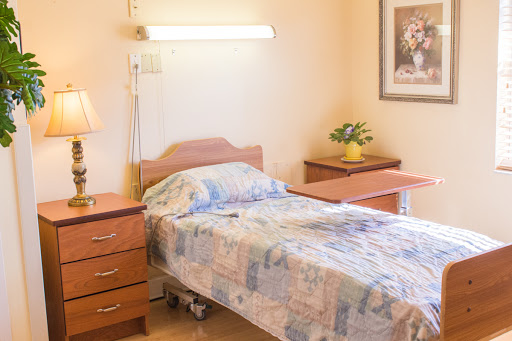 A cozy hospital room featuring a single bed, bedside table, and decorative elements.