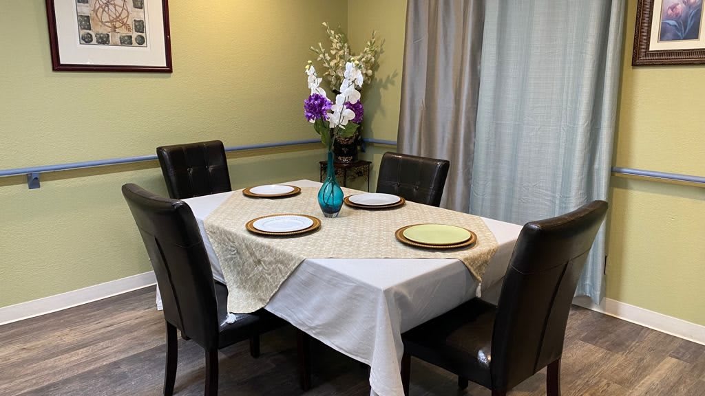 A neatly set dining table with a floral centerpiece and four chairs.