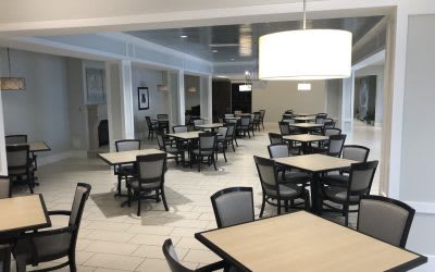 An empty cafeteria with neatly arranged tables and chairs.