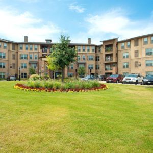 A residential apartment building with well-maintained landscaping and a spacious lawn area in front.
