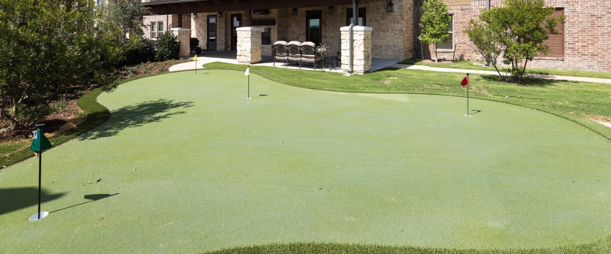 A well-maintained putting green in front of a building.