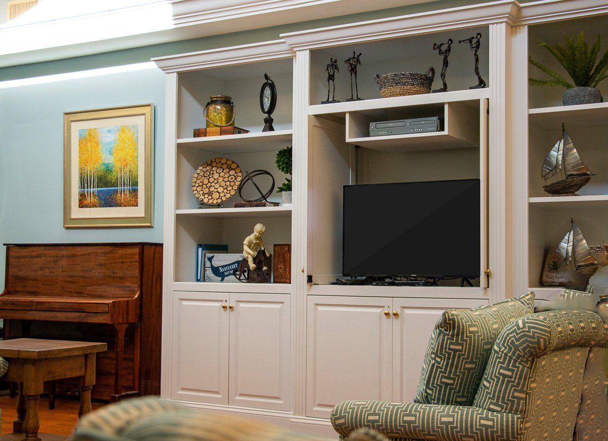 A cozy living room featuring an entertainment center with shelves and a television.