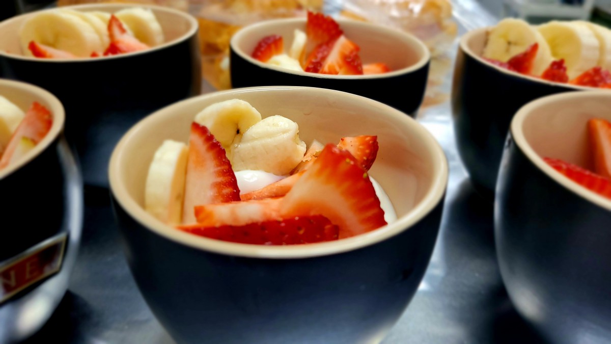 Bowls of yogurt topped with fresh strawberries and banana slices.