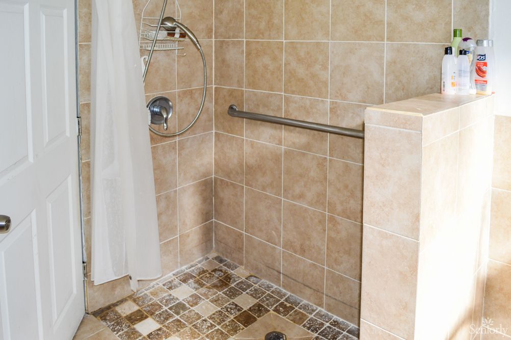 A tiled walk-in shower with a grab bar for support.