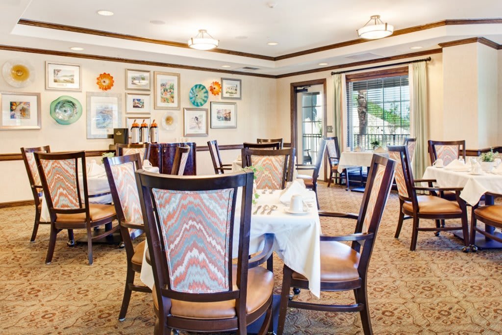 A cozy dining room with elegantly set tables and artistic decor on the walls.