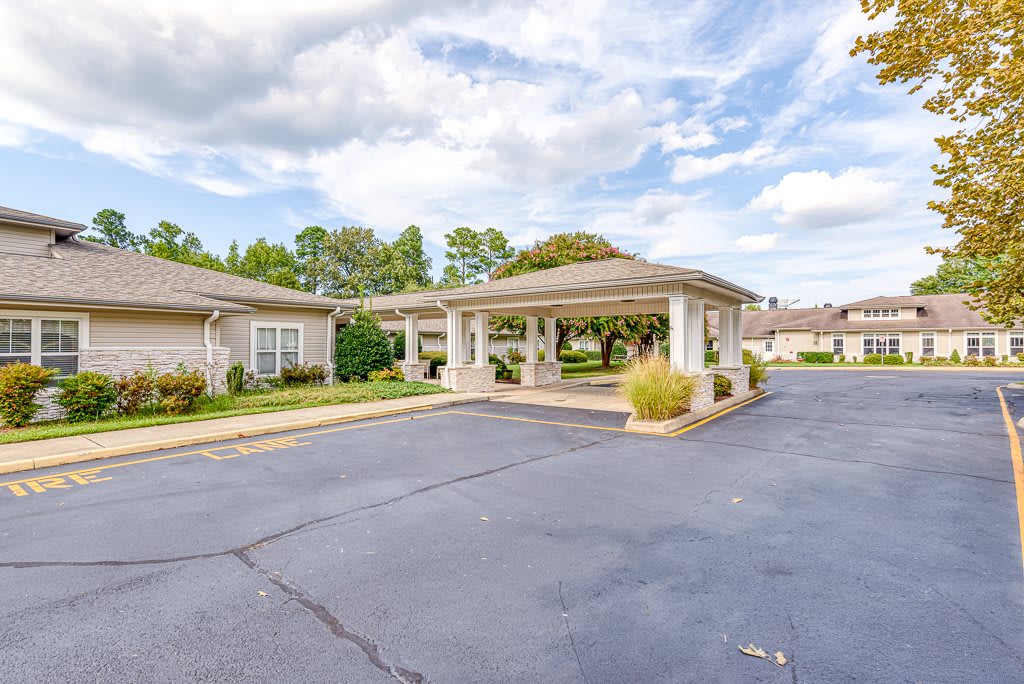A residential building with a covered driveway and well-maintained landscaping under a cloudy sky.