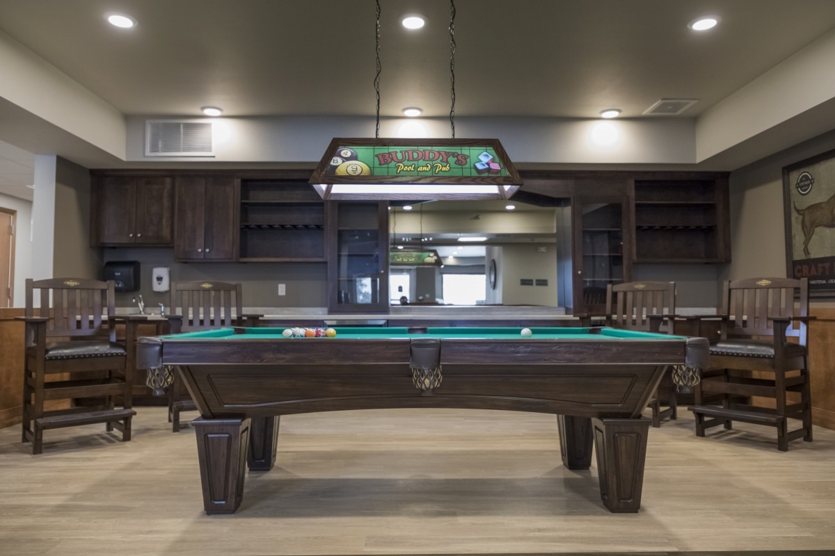 A stylish game room featuring a billiard table with a hanging light fixture above.