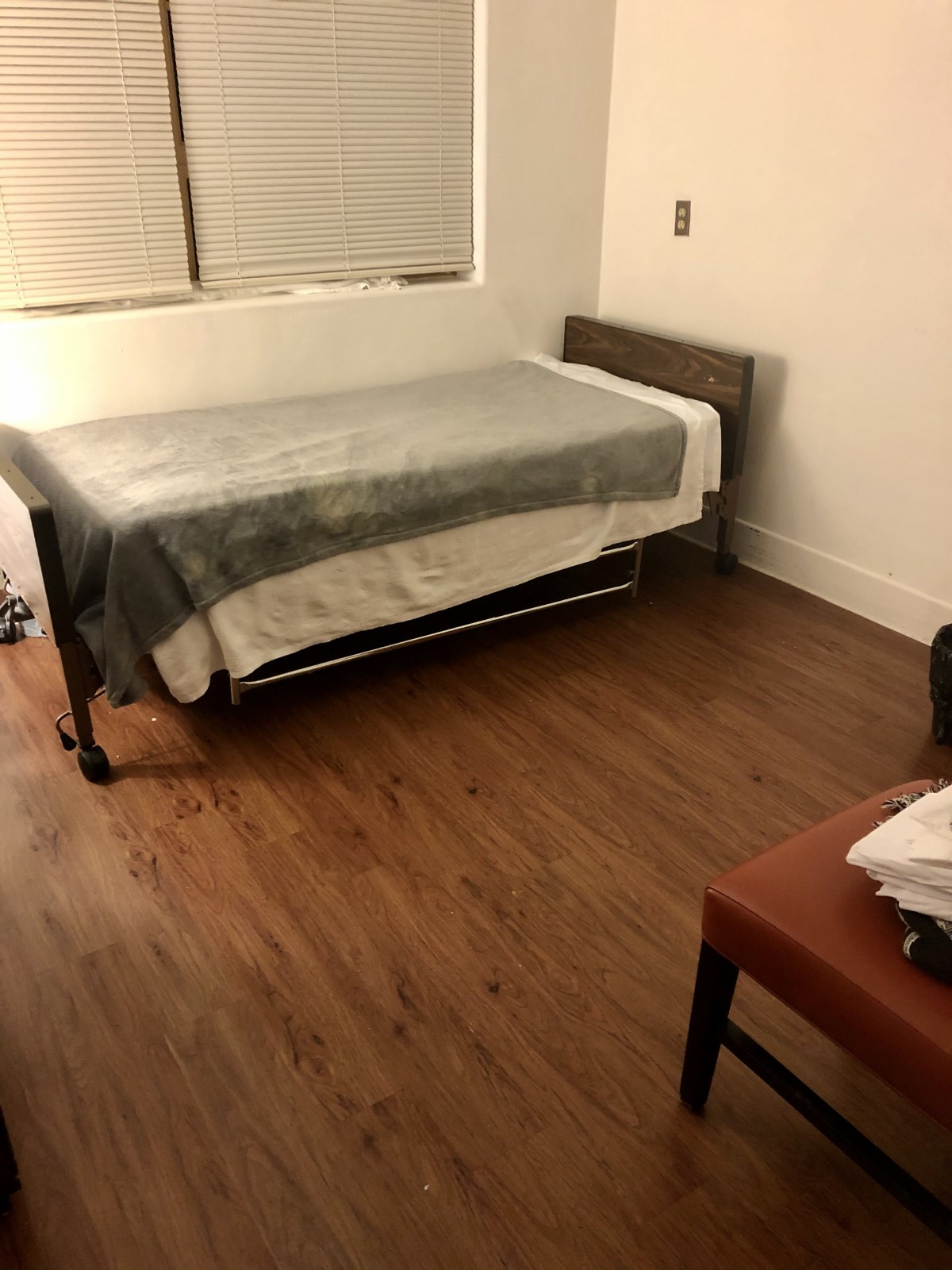 A simple and minimalist bedroom with a single bed and wooden flooring.