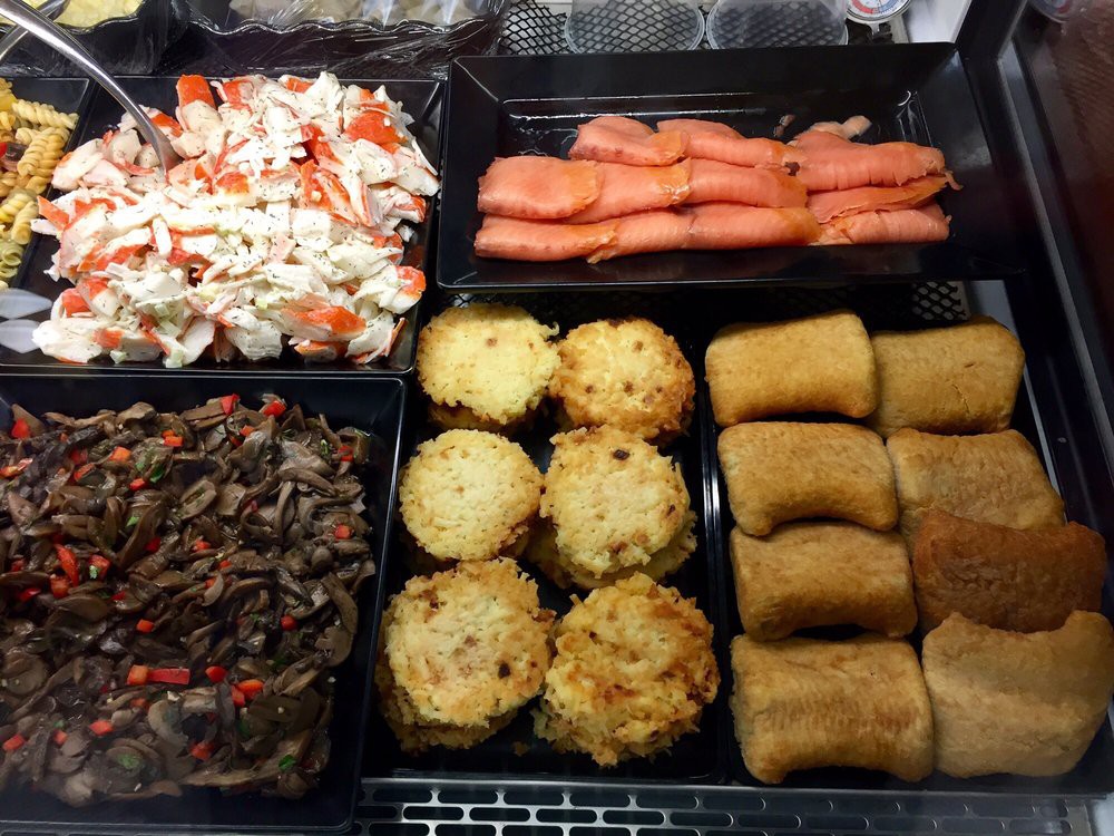 An assortment of buffet items including crab meat, smoked salmon, mushrooms, pastries, and other appetizers.