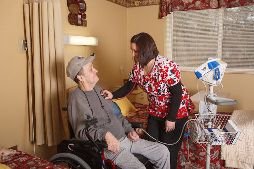 A caregiver attending to an elderly patient in a comfortable healthcare setting.