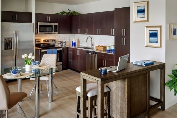 A modern kitchen with dark wood cabinets, stainless steel appliances, and a cozy dining area.