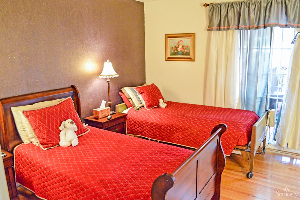 A cozy bedroom with twin beds featuring red bedding and wooden furniture.