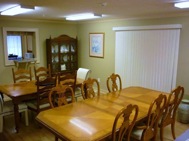 A dining room with wooden tables, chairs, and a cabinet.