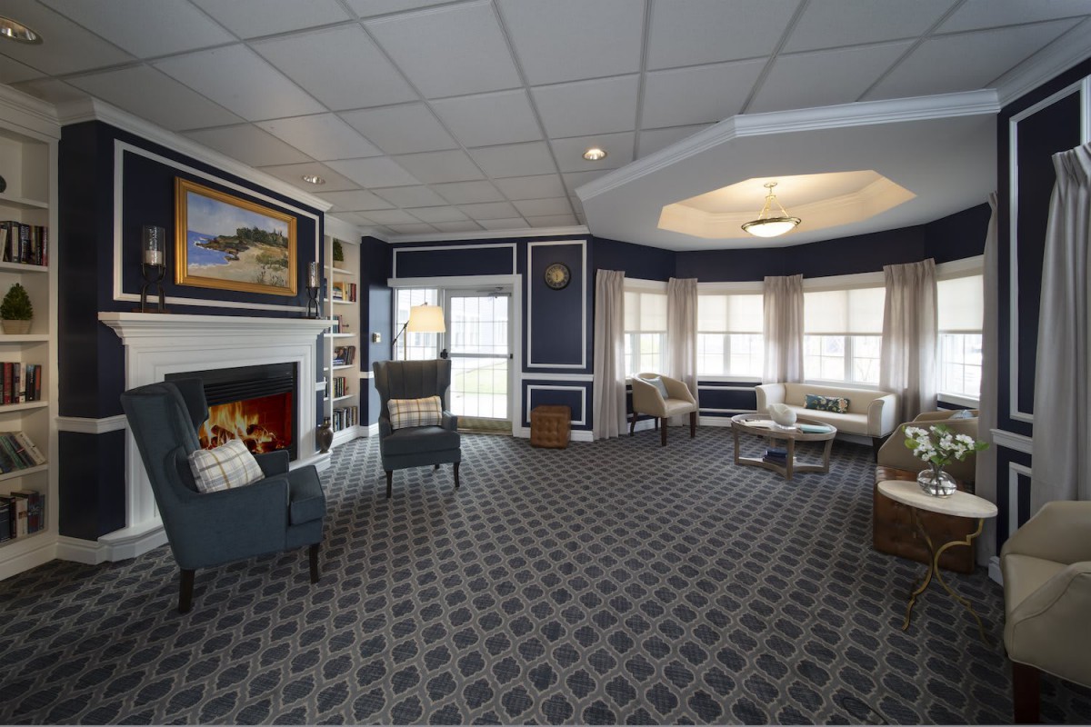A cozy interior room featuring a fireplace, comfortable seating, and large windows.