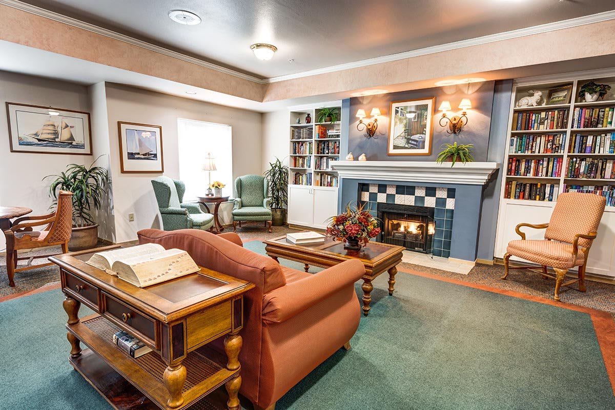 A cozy living room featuring a fireplace, bookshelves, and comfortable seating.