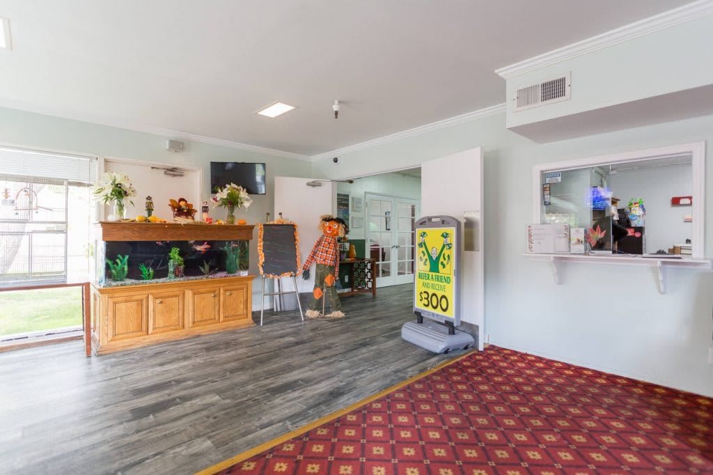 A well-lit hotel lobby featuring a reception desk, TV, and seating area.