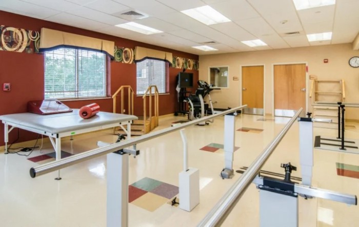 A well-equipped rehabilitation room with exercise equipment and walking bars.