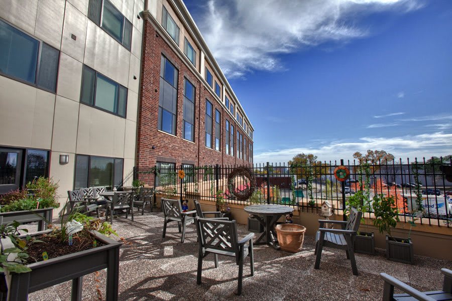 An outdoor patio area with seating and tables next to a building under a clear blue sky.