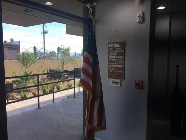 An American flag placed inside a building near the entrance, accompanied by a sign on the wall.