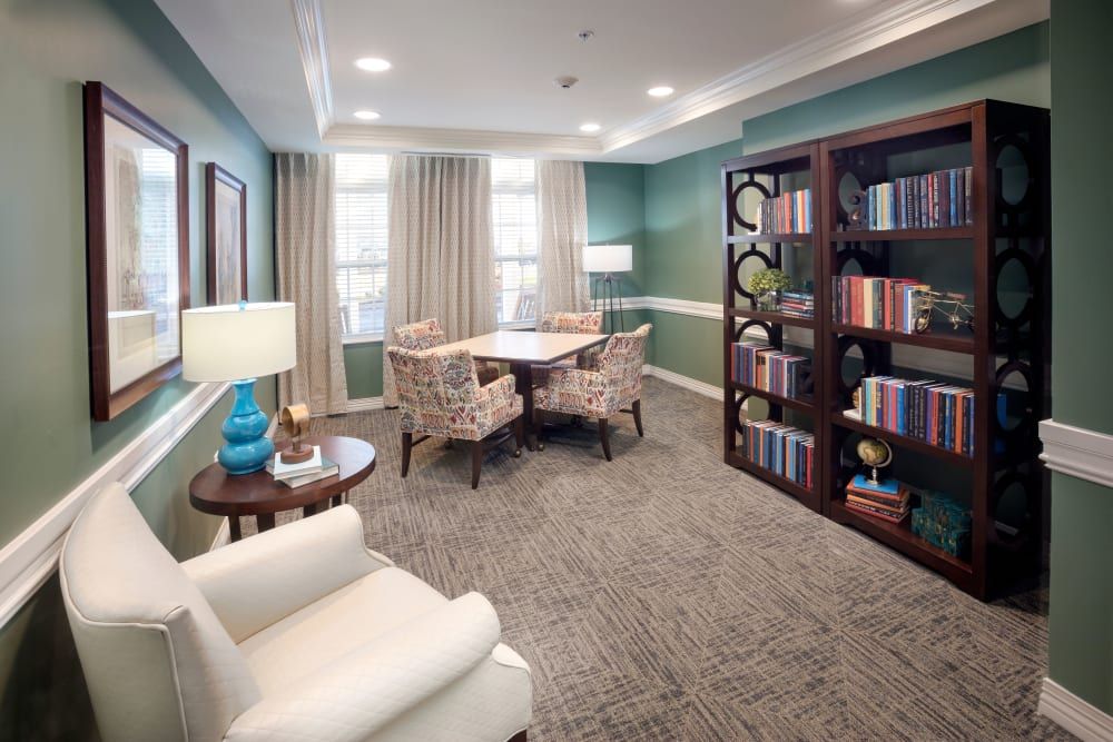 A cozy living room with a table, chairs, and a well-stocked bookshelf.