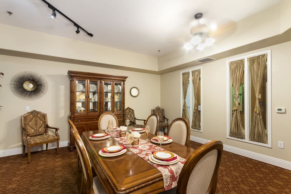 A traditional dining room featuring a wooden table set with plates and a china cabinet in the background.