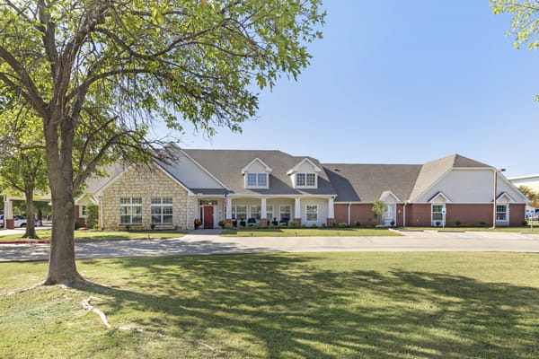 A large suburban house with a well-kept lawn and clear blue sky.