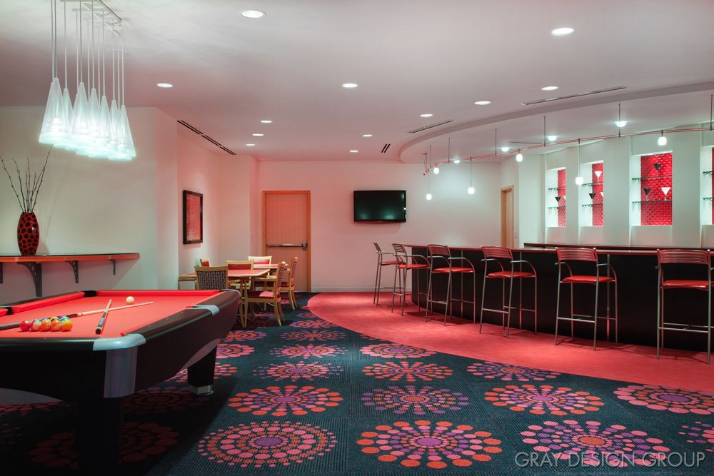 A stylish recreation room featuring a pool table and bar area with vibrant carpet design.