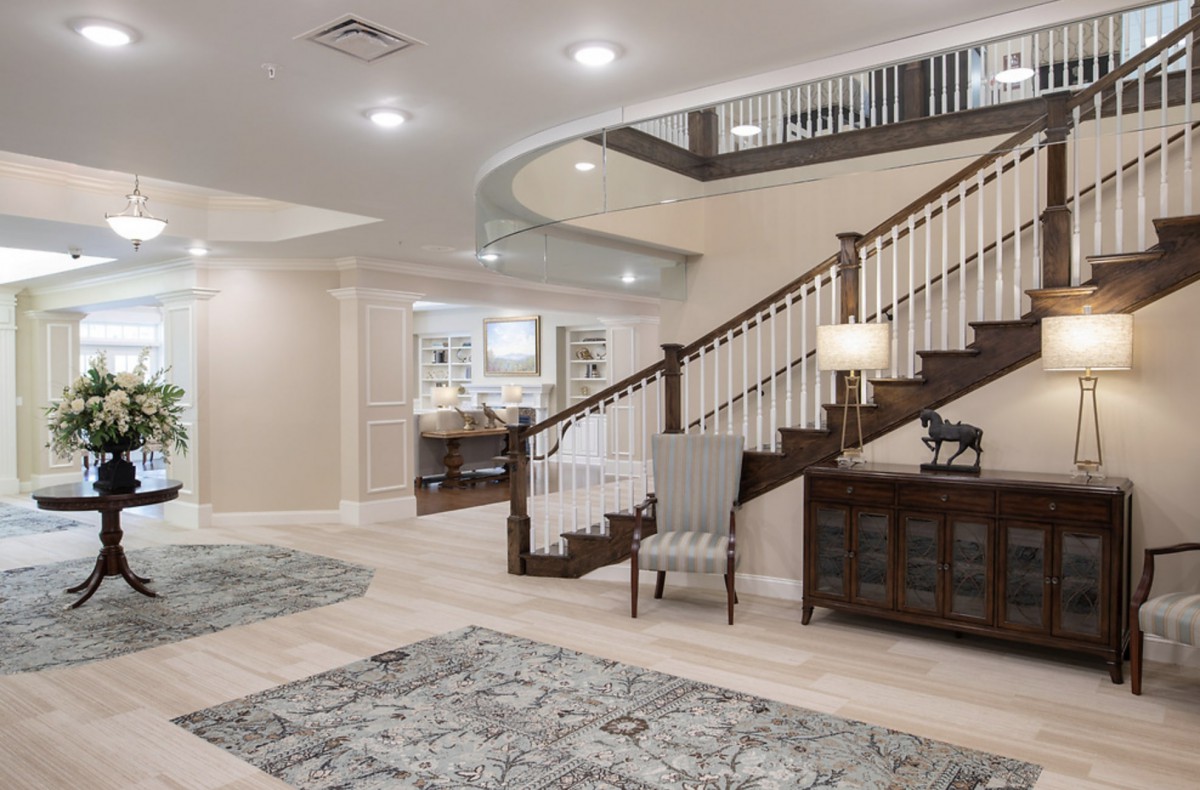 A spacious and elegantly designed interior featuring a modern staircase and comfortable seating.