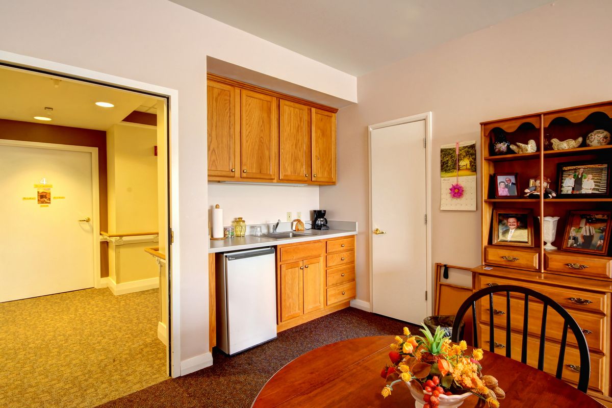 A cozy kitchenette area in an apartment with wooden cabinets and a small fridge.