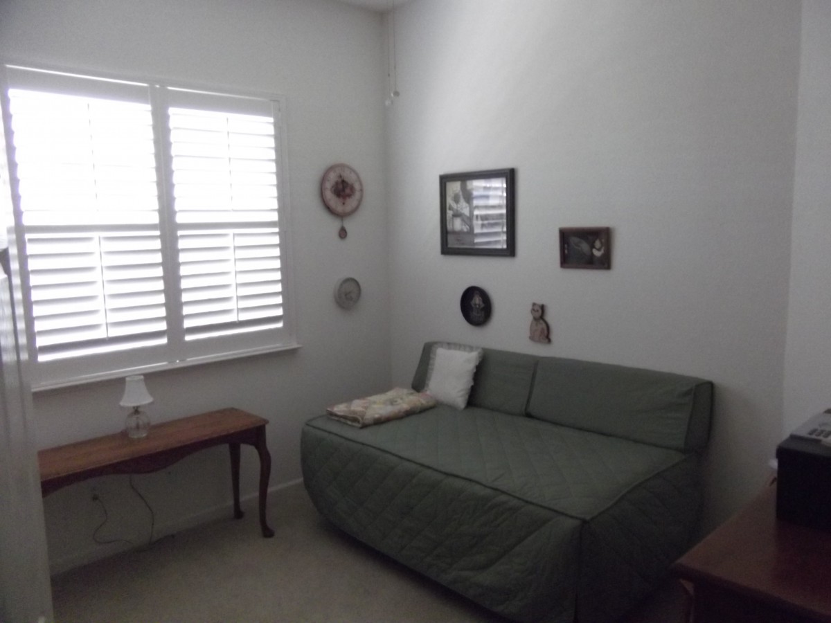 A cozy living room corner with a green sofa, wall decorations, and a small table by the window.