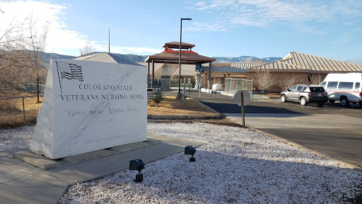 An exterior view of a facility featuring a prominent sign, with mountains in the background.