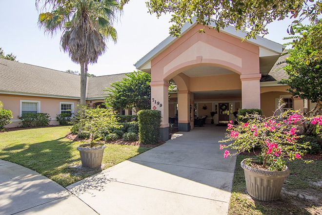 A welcoming entrance of a building surrounded by lush greenery and plants.