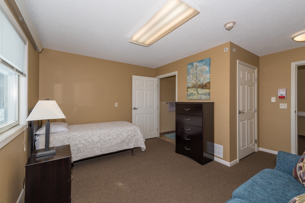 A cozy bedroom with a single bed, dresser, and warm color scheme.