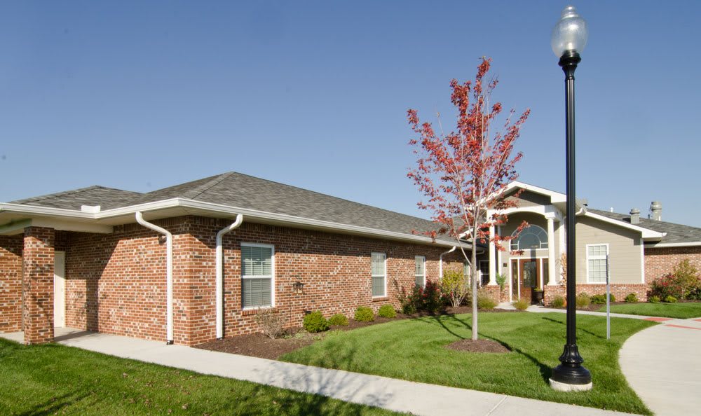 A brick residential house with a well-maintained garden and sidewalk.