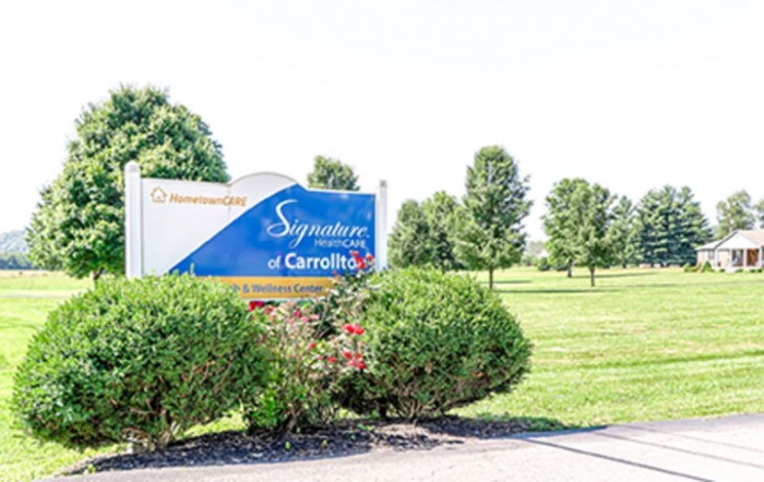 A sign for a nursing home facility surrounded by lush greenery.