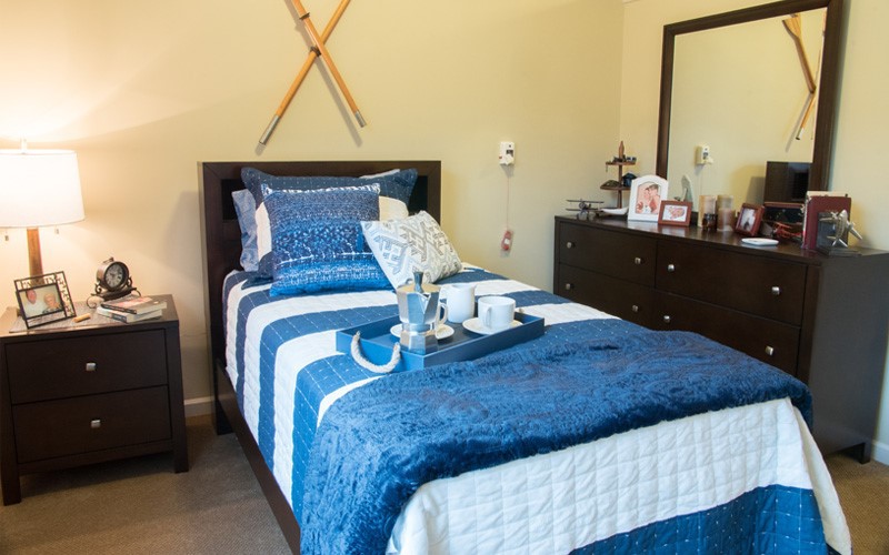 A cozy bedroom featuring blue bedding with modern decor and ski-themed wall art.